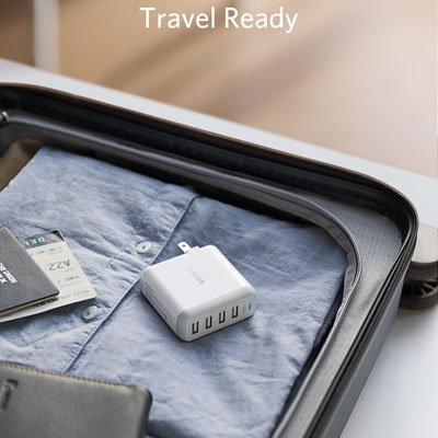 An Anker PowerPort 4 charger placed in travel case, which also packs clothes, a notebook, passport, and more
